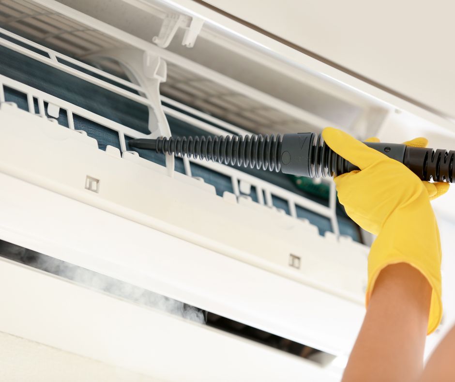 Person cleaning a split system air conditioning unit